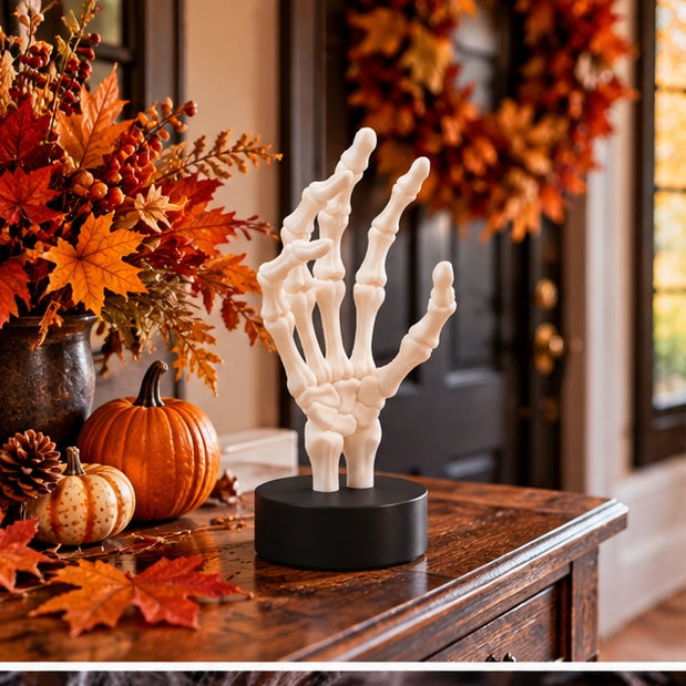 White skeletal hand on a black display base with warm autumn foliage in the background