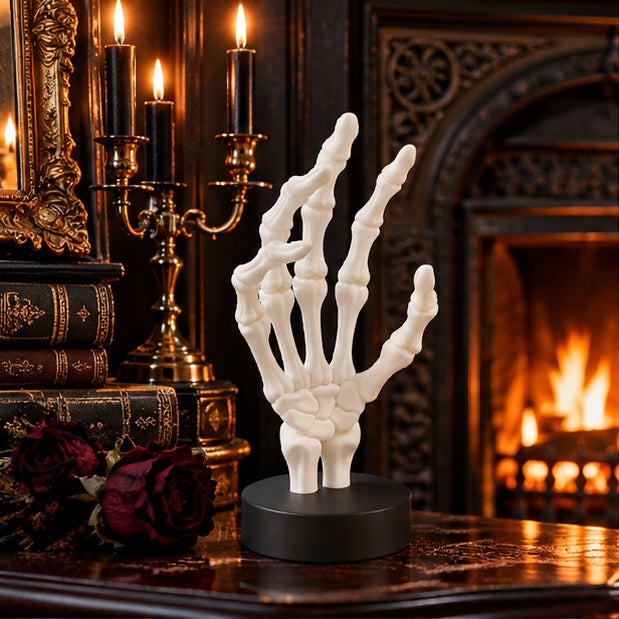 White skeletal hand on a rustic mantel with pumpkins, candles and autumn leaves